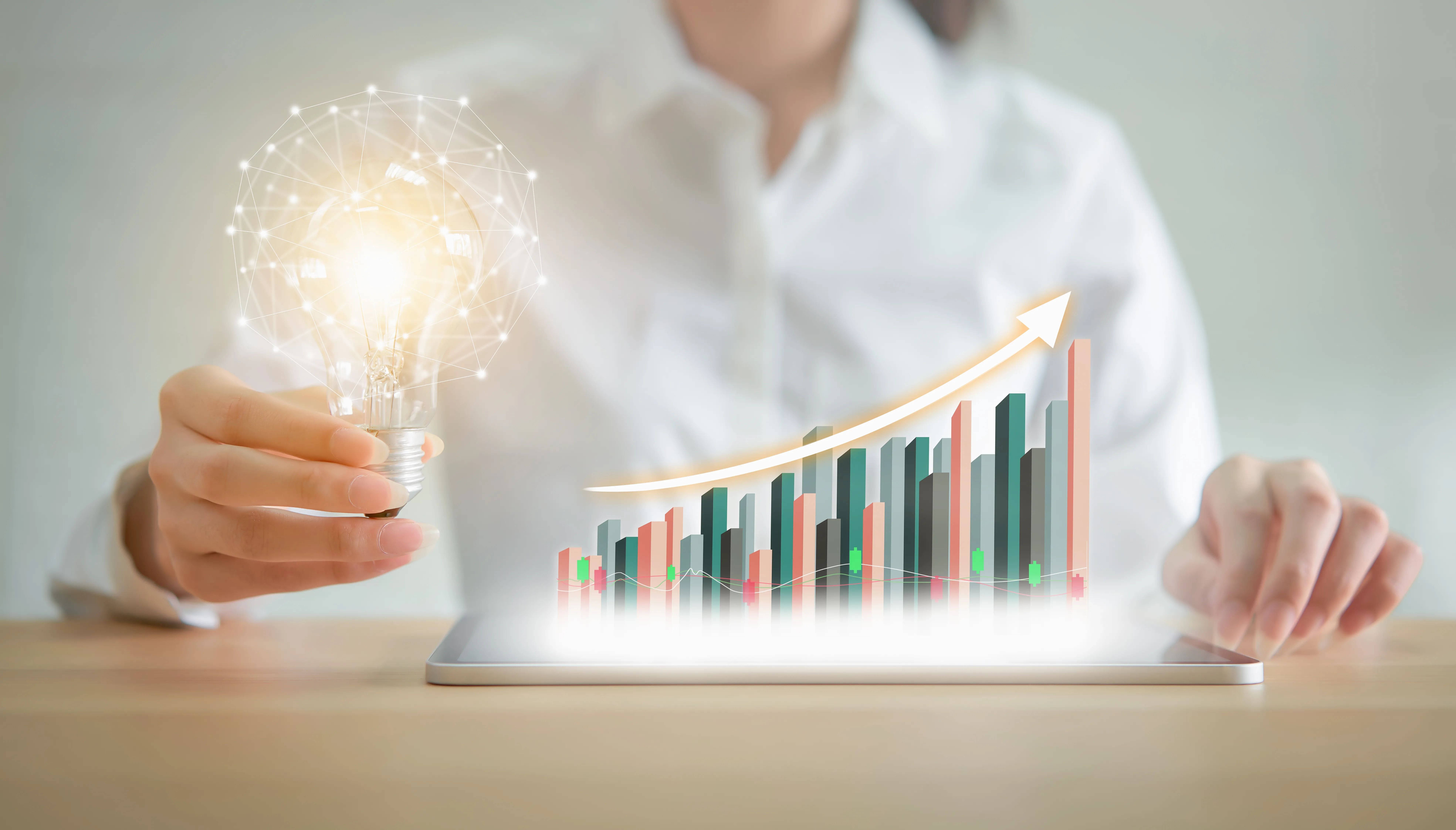 Businesswoman holding light bulb with innovative and creativity are keys to success. chart showing business growth on tablet. positive indication of income.